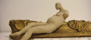 a small ceramic figure on part of an antique frame