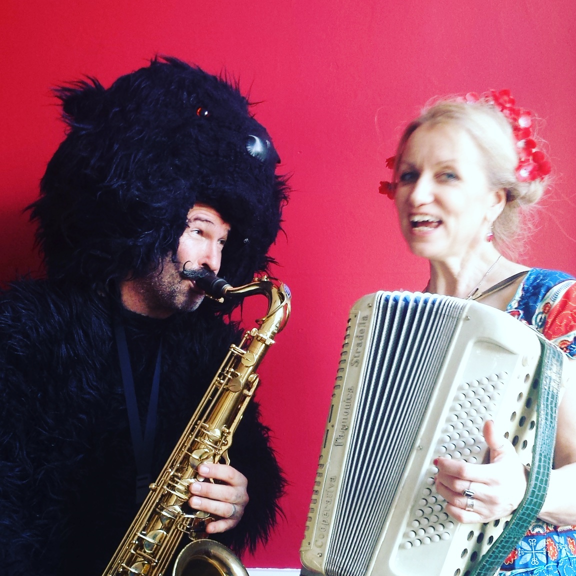 man dressed as bear playing a saxophone with a woman playing accordion