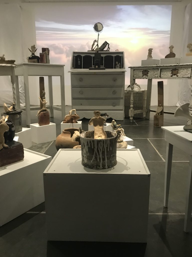 installation of small ceramic figures and domestic objects on furniture with projection of sunrise