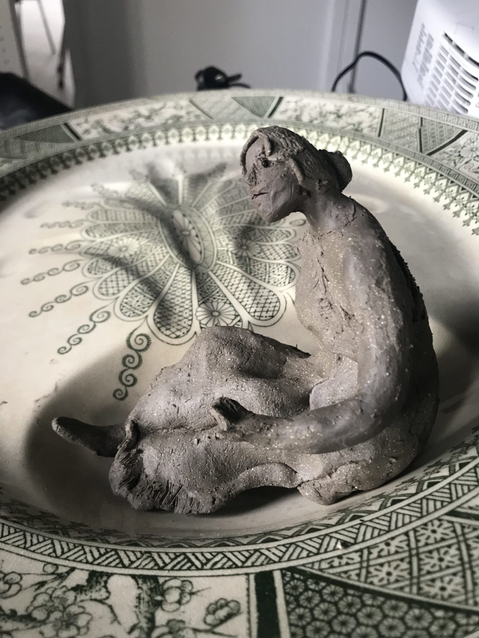 clay figure of a woman scaled to a found serving platter